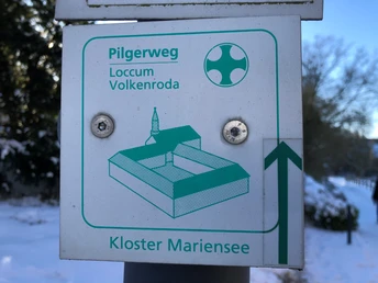 Loccum-Mariensee-Loccum Wegweiser für den Pilgerweg Loccum-Volkenroda mit Grafik des Kloster Mariensee bei winterlichem Wetter.