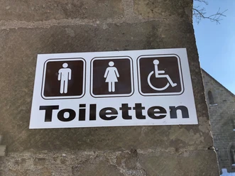 Toilettenschild am Kloster Loccum mit Symbolen für Herren, Damen und barrierefreien Zugang.