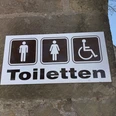 Toilettenschild am Kloster Loccum mit Symbolen für Herren, Damen und barrierefreien Zugang.