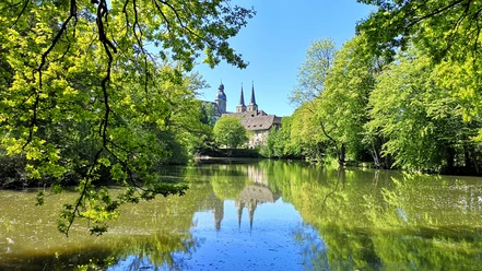 Blick auf die Abtei Marienmünster Abtei Marienmünster mit ihren markanten Türmen spiegelt sich in einem stillen, umgebenen Teich.
