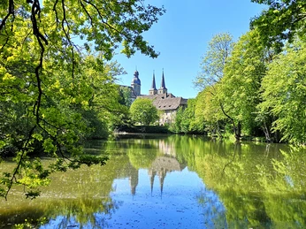 Blick auf die Abtei Marienmünster Abtei Marienmünster mit ihren markanten Türmen spiegelt sich in einem stillen, umgebenen Teich.