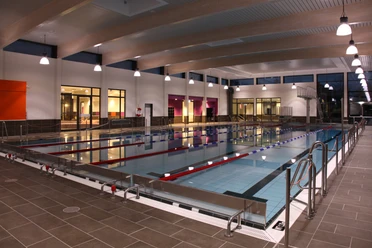 Schwimmvergnügen im GrönegauBad Melle Helles, modernes Hallenbad mit Schwimmbahnen, Lichtern und großen Fenstern im Hintergrund.