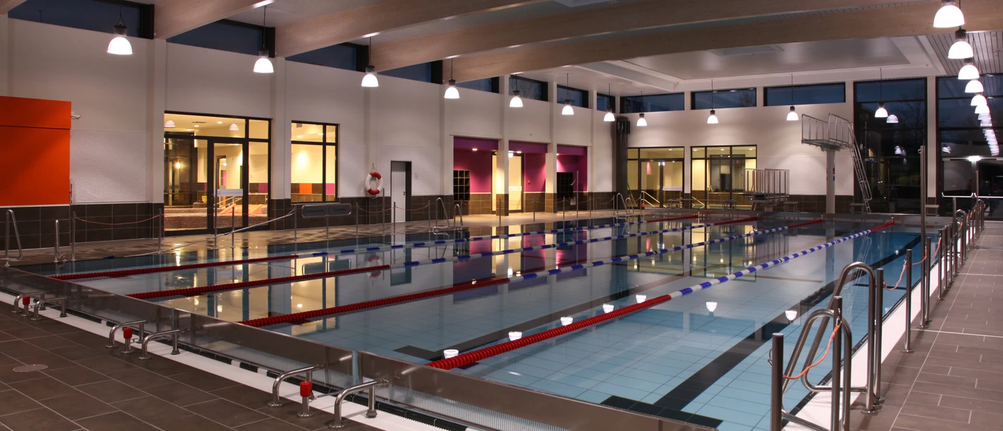 Schwimmvergnügen im GrönegauBad Melle Helles, modernes Hallenbad mit Schwimmbahnen, Lichtern und großen Fenstern im Hintergrund.