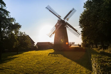 Lübbecke Windmühle Eilhausen Lübbecke Windmühle Eilhausen bei Sonnenuntergang, umgeben von grüner Wiese und Bäumen.