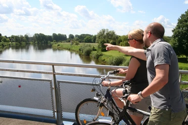 Weserbrücke Nienburg Zwei Radfahrer blicken von einer Brücke aus auf die beruhigende Weserlandschaft bei Nienburg.