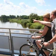 Weserbrücke Nienburg Zwei Radfahrer blicken von einer Brücke aus auf die beruhigende Weserlandschaft bei Nienburg.Two cyclists look out over the calming Weser landscape near Nienburg from a bridge.To cyklister kigger ud over det rolige Weser-landskab nær Nienburg fra en bro.Twee fietsers kijken vanaf een brug uit over het rustgevende landschap van de Weser bij Nienburg.