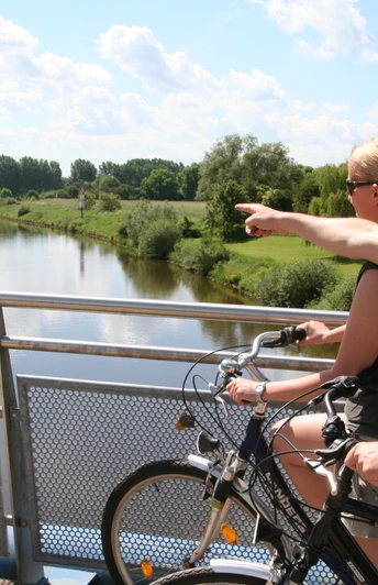 Weserbrücke Nienburg Zwei Radfahrer blicken von einer Brücke aus auf die beruhigende Weserlandschaft bei Nienburg.