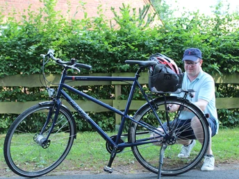 Radler Mittelweser Ein Mann sitzt neben einem blauen Fahrrad auf einem Radweg, umgeben von grünen Hecken und Holzzaun.A man sits next to a blue bicycle on a cycle path, surrounded by green hedges and a wooden fence.En mand sidder ved siden af en blå cykel på en cykelsti, der er omgivet af grønne hække og et træhegn.Een man zit naast een blauwe fiets op een fietspad, omringd door groene heggen en een houten hek.