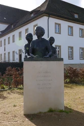 Denkmal Zigarrendreherinnen Bronzefiguren dreier Frauen, Symbol für die Zigarrendreherinnen, auf einem Sockel vor einem Gebäude.