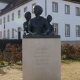 Denkmal Zigarrendreherinnen Bronzefiguren dreier Frauen, Symbol für die Zigarrendreherinnen, auf einem Sockel vor einem Gebäude.