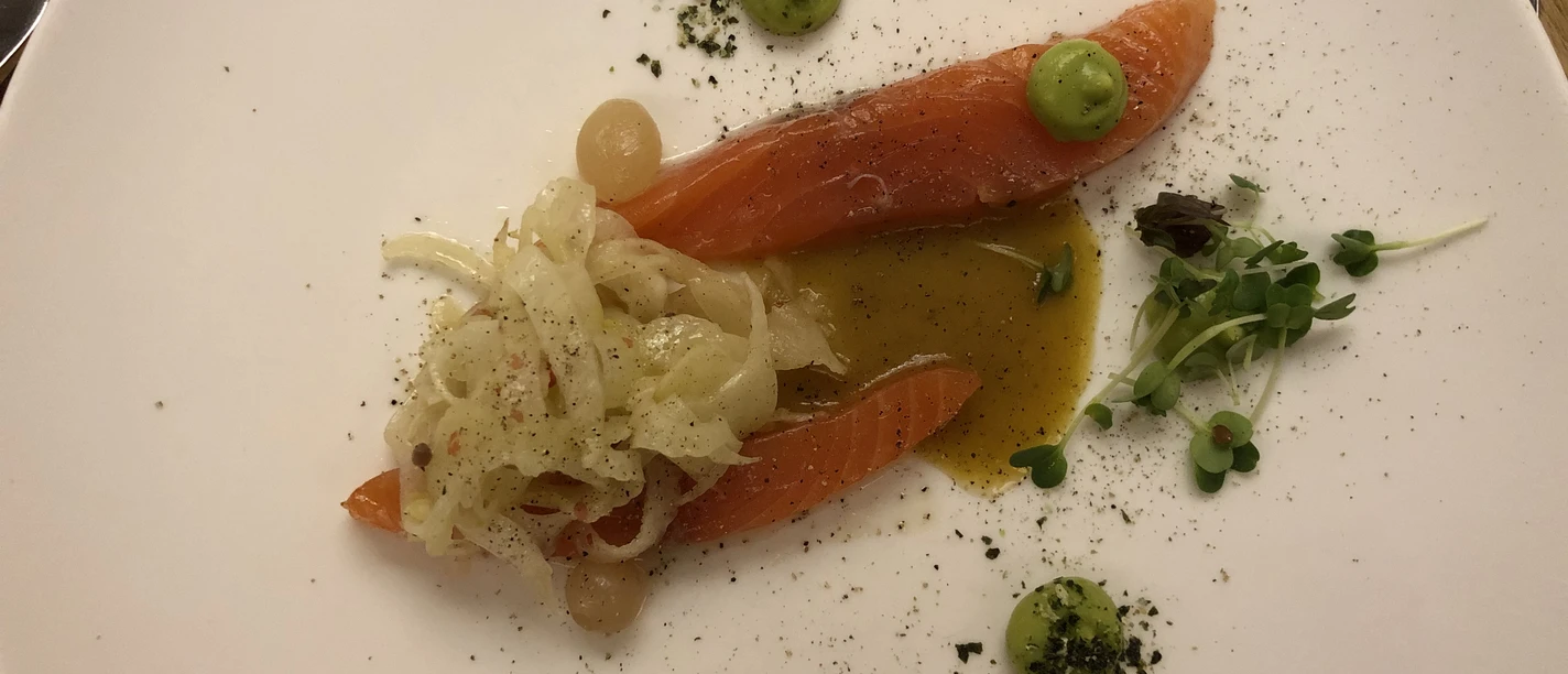 Salmon fillet with onion chutney and herb garnish, decoratively served on a white plate.