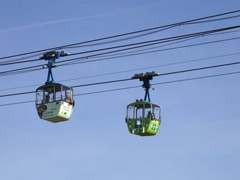 Kölner Seilbahn Zwei Seilbahngondeln gleiten vor strahlend blauem Himmel über Köln und bieten einen wunderbaren Ausblick.Two cable car gondolas glide over Cologne against a bright blue sky and offer a wonderful view.