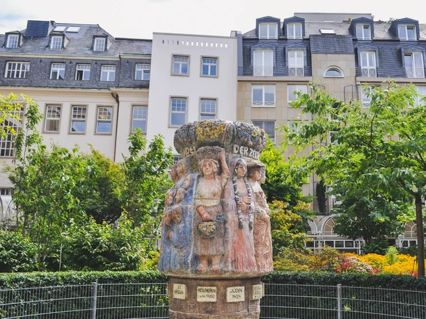 Frauenbrunnen Der Frauenbrunnen zeigt zehn lebensgroße Frauenfiguren "die Frauen Kölns im Wandel der Zeiten“, umgeben von üppigem Grün, vor urbaner Kulisse.