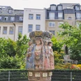 Women's fountain Der Frauenbrunnen zeigt zehn lebensgroße Frauenfiguren "die Frauen Kölns im Wandel der Zeiten“, umgeben von üppigem Grün, vor urbaner Kulisse. The Frauenbrunnen fountain shows ten life-size female figures "the women of Cologne through the ages", surrounded by lush greenery against an urban backdrop.