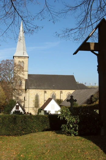 Pfarrkirche St. Margaretha mit spitzem Turm, umgeben von Bäumen und Kreuze am Friedhofsbereich.