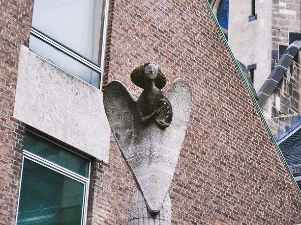 Angel statue A stone statue of an angel rises majestically from a red brick building.