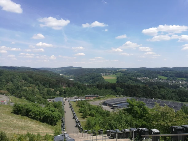 Ausblick von :metabolon Blick auf hügelige Landschaft bei Lindlar; im Vordergrund ein Weg, im Hintergrund Wälder und Felder.