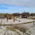 Trockenstrand Upleward Spielplatz Zu sehen sind mehrere Spielgeräte auf dem Trockenstrand in Upleward. Im Hintergrund der Deich,