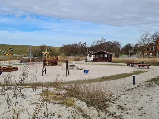 Trockenstrand Upleward Spielplatz Zu sehen sind mehrere Spielgeräte auf dem Trockenstrand in Upleward. Im Hintergrund der Deich,