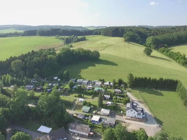 Luftbild Campingplatz.jpg Luftbild eines idyllischen Campingplatzes umgeben von grünen Wiesen und Wäldern in hügeliger Landschaft.