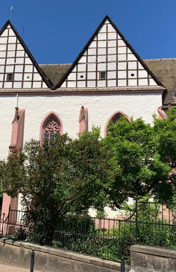 Eine gotische Kirchenfassade mit dreieckigen Giebeln und Spitzbogenfenstern unter strahlend blauem Himmel.
