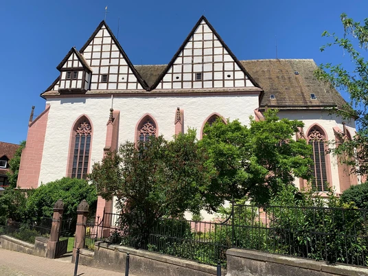 Eine gotische Kirchenfassade mit dreieckigen Giebeln und Spitzbogenfenstern unter strahlend blauem Himmel.