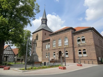 Martiniturm Blomberg neben historischem Gebäude, ergänzt durch Stolpersteine im Vordergrund.