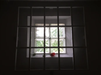 Arrestzelle in der Gedenkstätte Stalag 326 VIK Fenster in einer Arrestzelle mit Außengitter in der Gedenkstätte Stalag 326 VI K, rote Rose liegt.