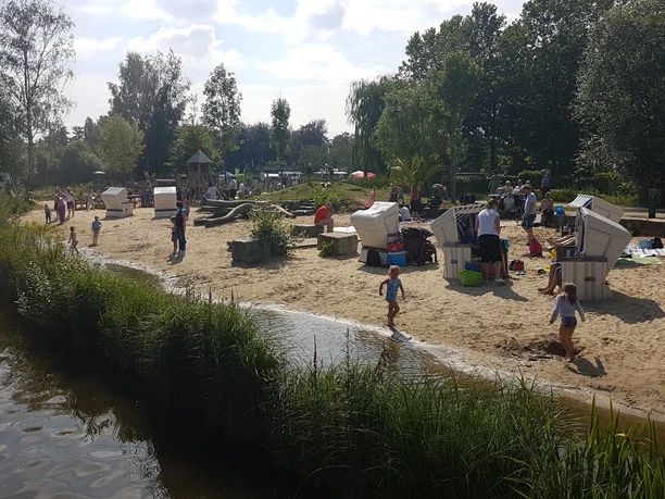 Sandstrand am Obersee Menschen genießen einen sonnigen Tag am Sandstrand mit Strandkörben an einem kleinen See.