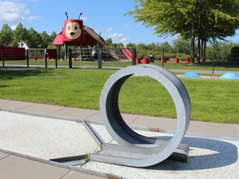 Minigolfanlage im Gartenschaupark Spielplatz mit Marienkäfer-Themenrutsche, Rasenflächen und modernem Kunst-Spielgerät im Vordergrund.
