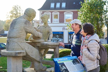 Töpferdenkmal Tellingstedt Steinskulptur eines Töpfers mit Kind und Besuchern