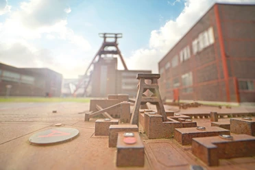 RevierRoute Probierstück.jpg <p>Miniaturmodell der Zeche Zollverein mit Förderturm und historischen Backsteingebäuden im Hintergrund.</p>