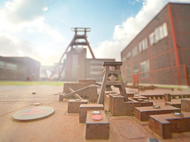 RevierRoute Probierstück.jpg <p>Miniaturmodell der Zeche Zollverein mit Förderturm und historischen Backsteingebäuden im Hintergrund.</p>