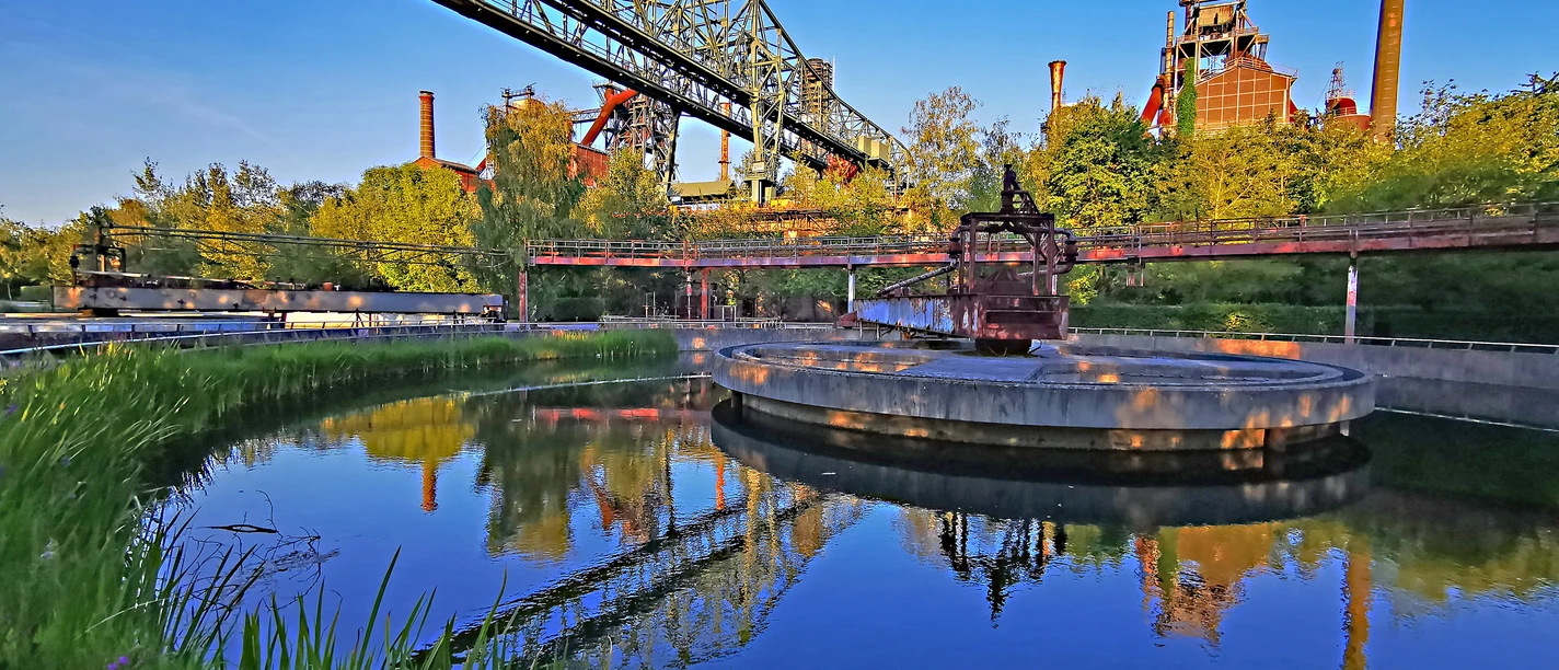 RevierRoute Stahlküche <p>Industrieanlage im Landschaftspark Duisburg-Nord mit Wasserbecken, blauer Himmel und grüner Natur.</p>