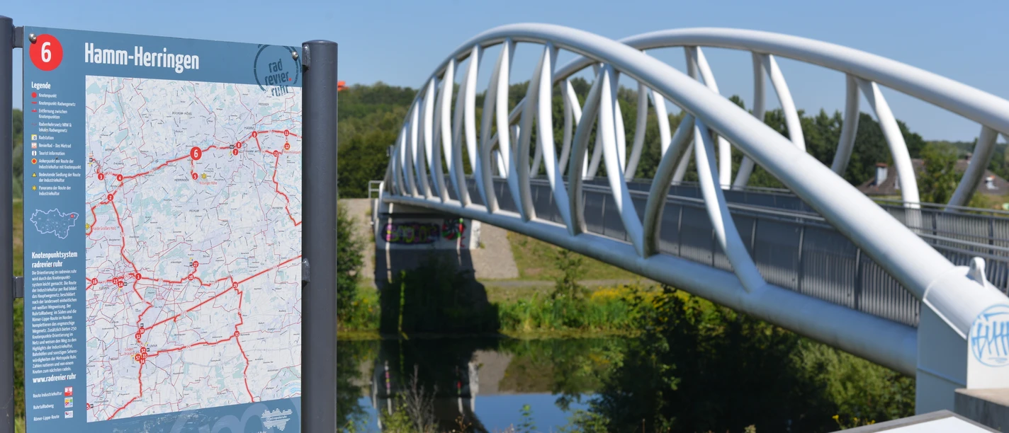 RevierRoute Elefantenrunde Moderne Brücke über Kanal neben Infotafel mit Streckenkarten.