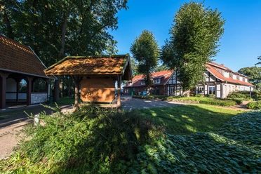 Bioland Hof Vaal Eingangsbereich des Bioland-Hofs Vaal mit Hofschild, Fachwerkgebäuden und grünen Bäumen im Sonnenschein.