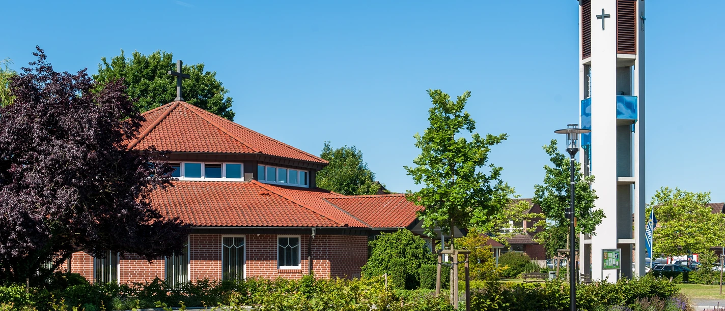 Ev.-luth. Gemeindezentrum Backsteinkirche mit achteckigem Dach und modernem Glockenturm neben bepflanztem Vorplatz