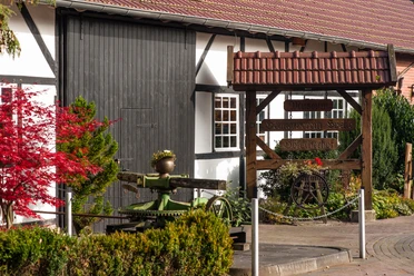 Museumsscheune „Hölscherhof“ Holzbeschilderter Eingang zur Museumsscheune Hölscherhof mit Fachwerkfassade und Gartenpflanzen