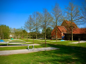 Minigolfplatz mit modernen Bahnen in idyllischer ländlicher Umgebung, umgeben von grünen Bäumen.