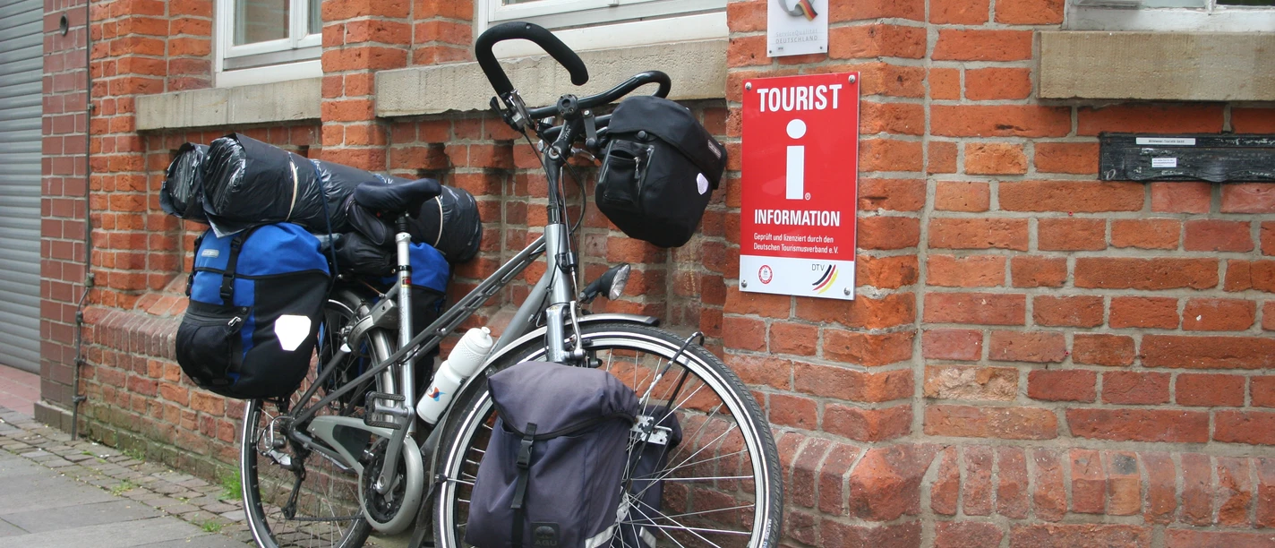 Tourist-Information Nienburg Een beladen fiets leunt tegen het rode bakstenen gebouw van het Nienburg Tourist Information Centre.