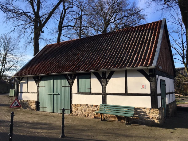 Remise am Wöhlehof Fachwerkhaus mit rotem Ziegeldach, grün gestrichenen Türen und Bank vor dem Eingang.
