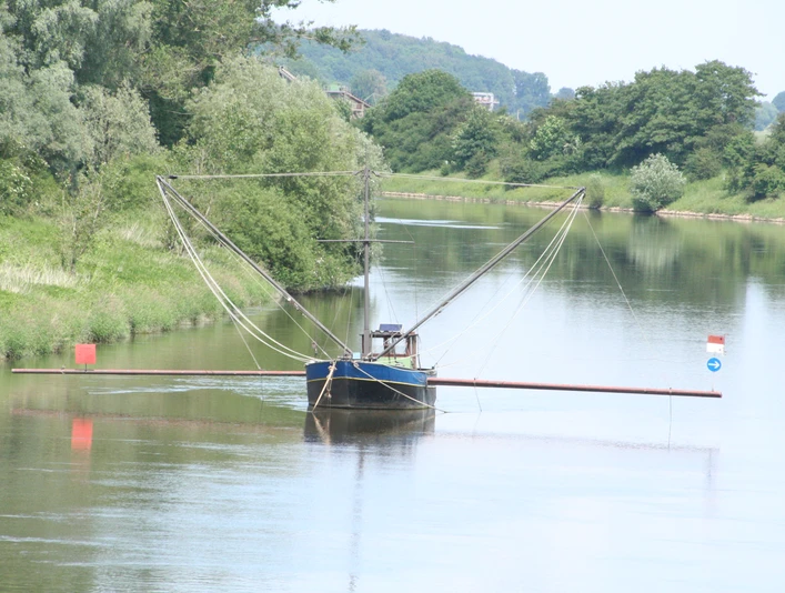 Ein traditioneller Aalschokker auf einem ruhigen Fluss, umgeben von grünen Bäumen und sanften Hügeln.A traditional eel barge on a quiet river, surrounded by green trees and rolling hills.En traditionel ålepram på en stille flod, omgivet af grønne træer og bølgende bakker.Een traditionele palingaak op een rustige rivier, omringd door groene bomen en glooiende heuvels.