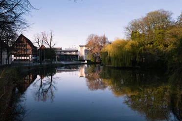 Blick auf das Lippische Landesmuseum in Detmold Spiegelung des Lippischen Landesmuseums und umgebender Bäume im ruhigen Wasser eines Teichs im Frühling.