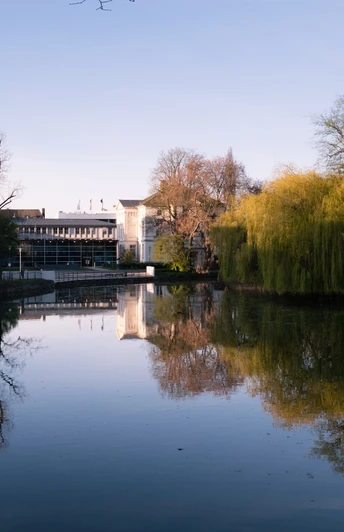 Blick auf das Lippische Landesmuseum in Detmold Spiegelung des Lippischen Landesmuseums und umgebender Bäume im ruhigen Wasser eines Teichs im Frühling.