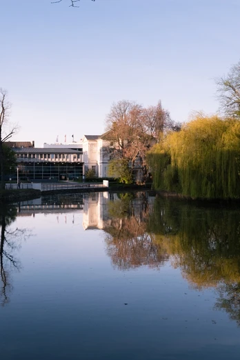 Blick auf das Lippische Landesmuseum in Detmold Spiegelung des Lippischen Landesmuseums und umgebender Bäume im ruhigen Wasser eines Teichs im Frühling.