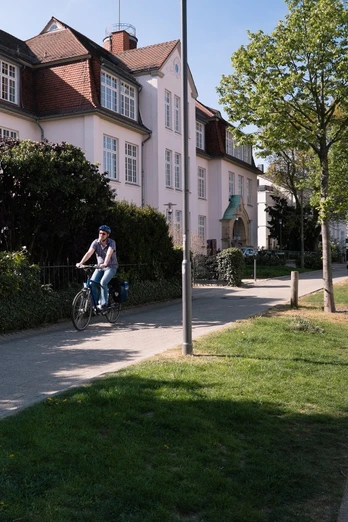 Friedrichstaler Kanal Detmold Ein Radfahrer auf einem asphaltierten Weg neben dem Friedrichstaler Kanal, umgeben von Bäumen und Häusern.