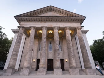 Klassizistisches Gebäude mit monumentalen Säulen und symmetrischer Fassade unter freiem Himmel.