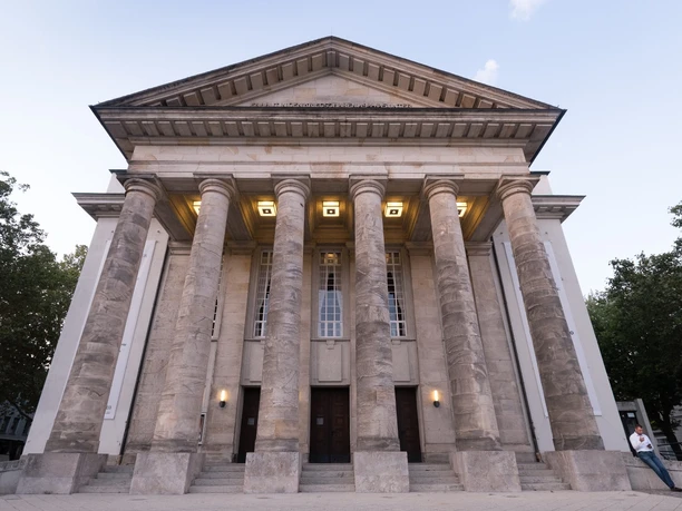 Klassizistisches Gebäude mit monumentalen Säulen und symmetrischer Fassade unter freiem Himmel.