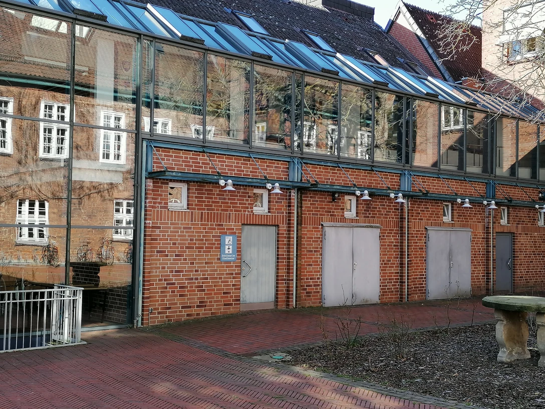 Barrierefreie Toilette am Rathaus, Backsteingebäude mit Glaselementen; links Rampe für Rollstuhlfahrer.