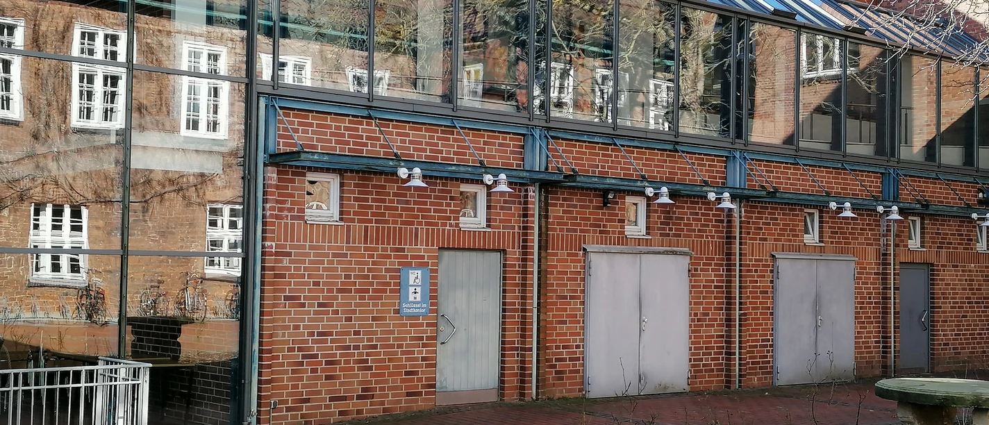 Barrierefreie Toilette am Rathaus, Backsteingebäude mit Glaselementen; links Rampe für Rollstuhlfahrer.